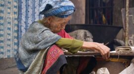 Seorang penenun perempuan di Sumba sedang merangkai benang bermotif tradisional dengan menggunakan teknik pewarnaan alami yang diwariskan secara turun-temurun.