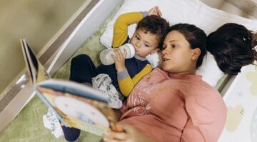 Seorang ibu membacakan buku cerita rakyat bergambar kepada anaknya sebelum tidur untuk membangun ikatan emosional dan mengenalkan kebudayaan Nusantara sejak dini.